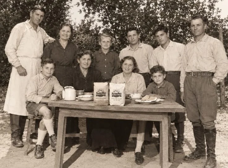 Composición de campaña en blanco y negro con un grupo familiar alrededor de una mesa y productos Kalitko